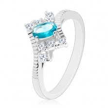 Prsten ve stříbrné barvě, oválný světle modrý zirkon, zářezy na ramenech