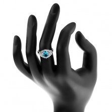 Třpytivý prsten se světle modrým oválným zirkonem, čirá zirkonová obruba
