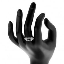 Lesklý prsten ve stříbrném odstínu, blýskavá mašlička s černým oválem